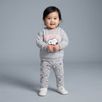 Bebé niña sonriente con conjunto EmpiBy gris de dos piezas con estampado de Snoopy y corazón rojo