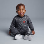 Bebé sonriente vistiendo conjunto EmpiBy de dos piezas de Spider-Man en gris melange con estampado de telaraña.