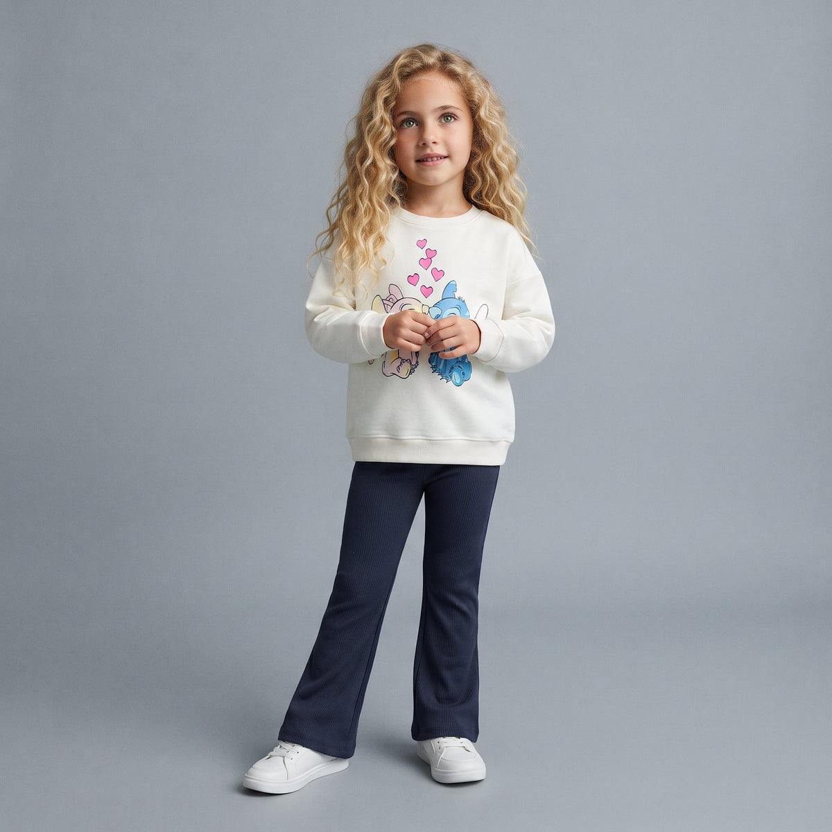 Niña vistiendo conjunto EmpiBy de sudadera color hueso con estampado de Stitch y Angel y pantalón azul marino