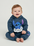 Bebé sonriente vistiendo conjunto EmpiBy de sudadera y jogger azul de Stitch con capucha y orejas en relieve