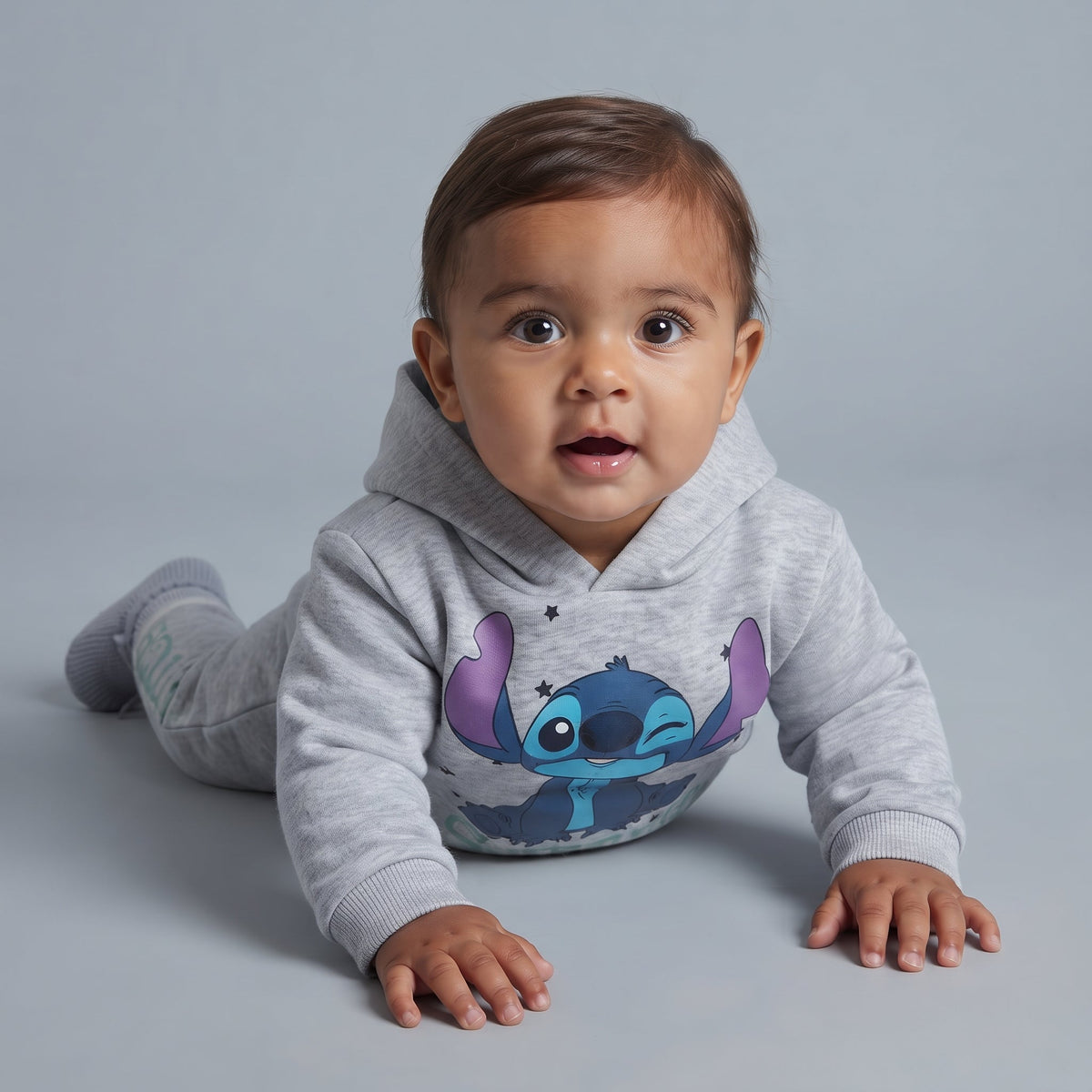 Bebé con conjunto EmpiBy de dos piezas gris jaspeado con sudadera con capucha y gráfico de Stitch guiñando un ojo