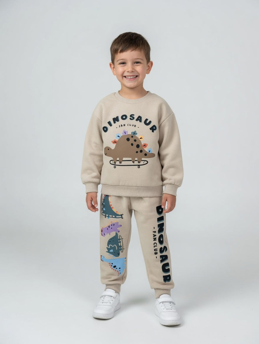 Niño sonriente vistiendo conjunto EmpiBy beige de sudadera y pantalón con estampado de dinosaurios skaters