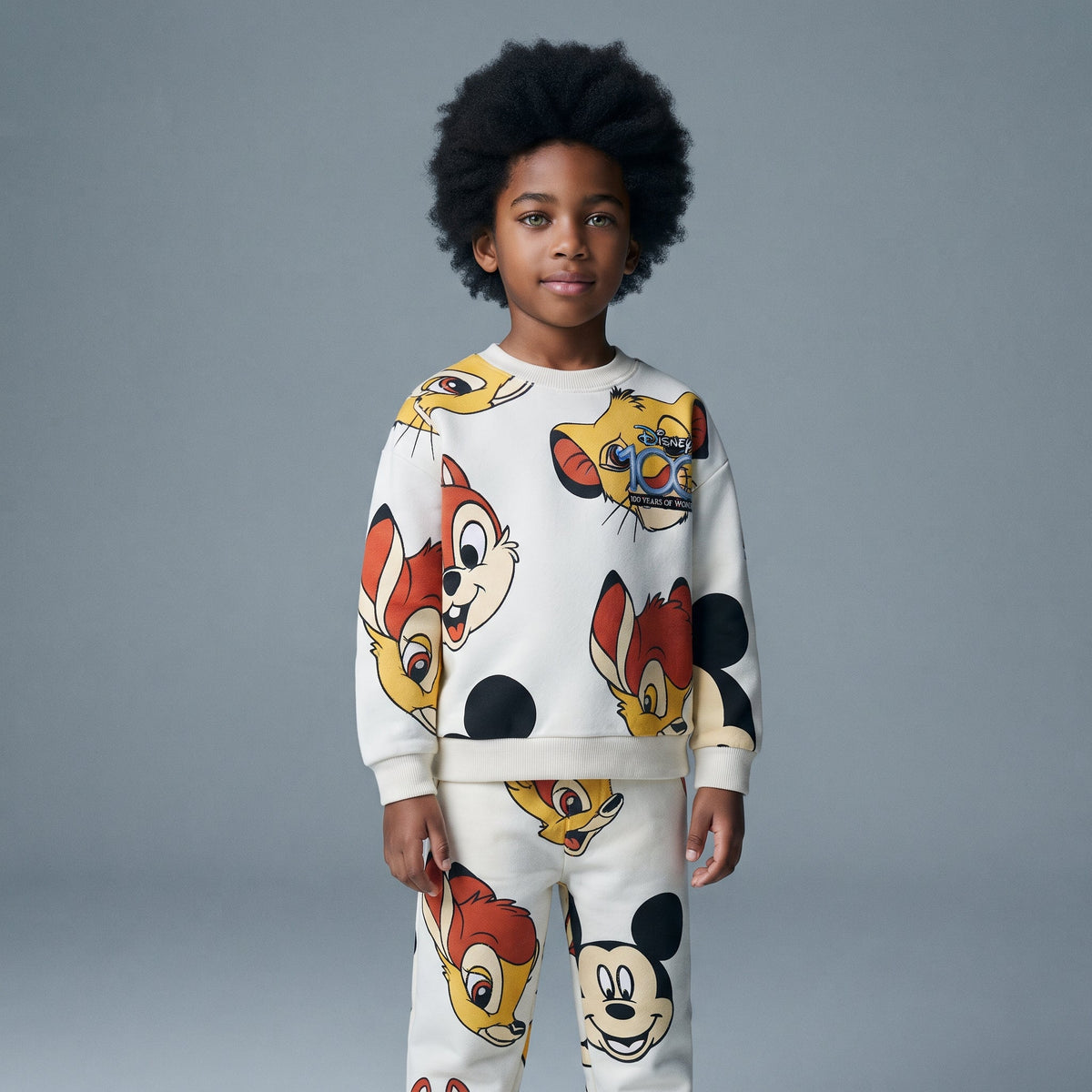 Niño vistiendo conjunto EmpiBy de sudadera y pantalón con estampado colorido de personajes clásicos de Disney