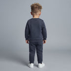 Niño de espaldas vistiendo conjunto EmpiBy de sudadera y pantalón jogger gris oscuro de Paw Patrol con zapatillas