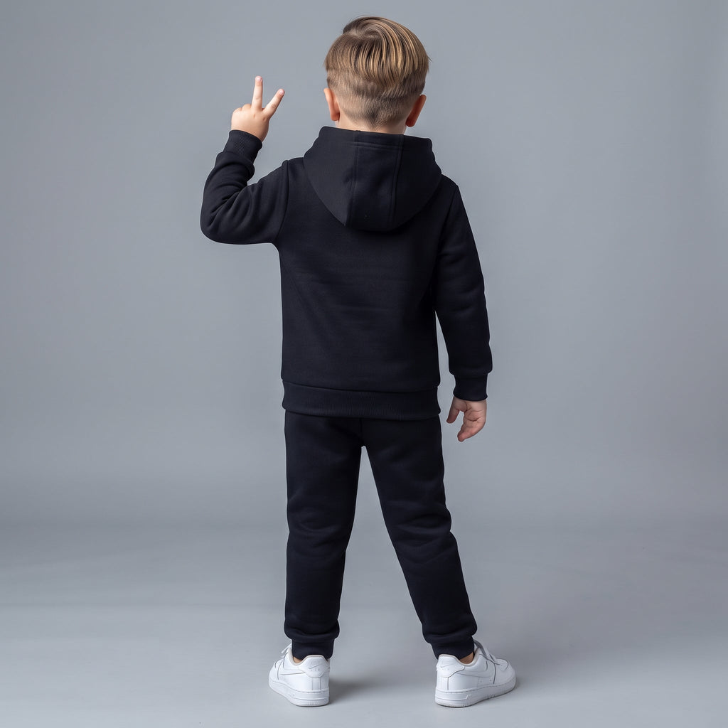 Niño de espaldas vistiendo conjunto EmpiBy de sudadera con capucha y pantalón jogger negro, estilo deportivo casual.