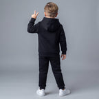Niño de espaldas vistiendo conjunto EmpiBy de sudadera con capucha y pantalón jogger negro, estilo deportivo casual.