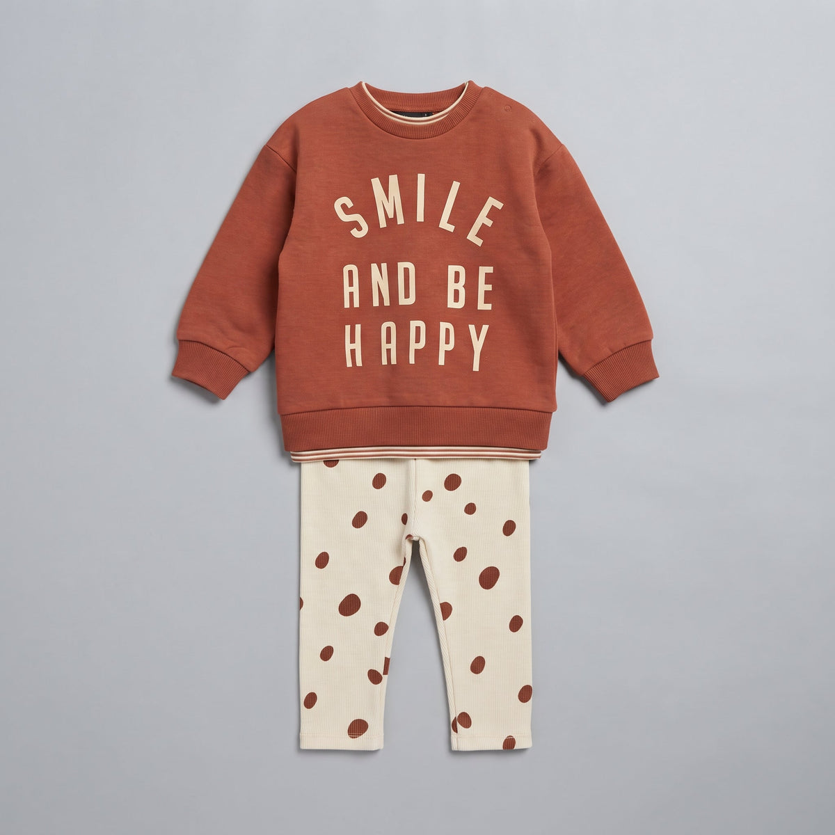 Conjunto EmpiBy de dos piezas para bebé: sudadera terracota con frase y legging marfil con lunares, tejido acanalado.