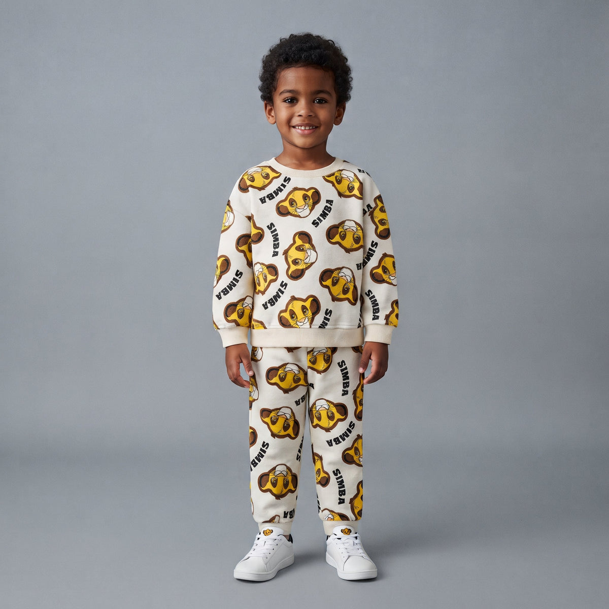 Niño sonriente vistiendo conjunto EmpiBy de sudadera y jogger color crema con estampado de Simba de El Rey León