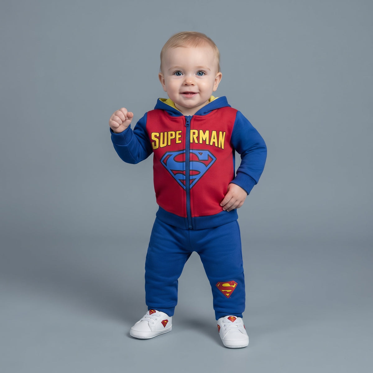 Bebé con conjunto EmpiBy de Superman de dos piezas, sudadera roja y azul con cremallera y pantalón jogger a juego.