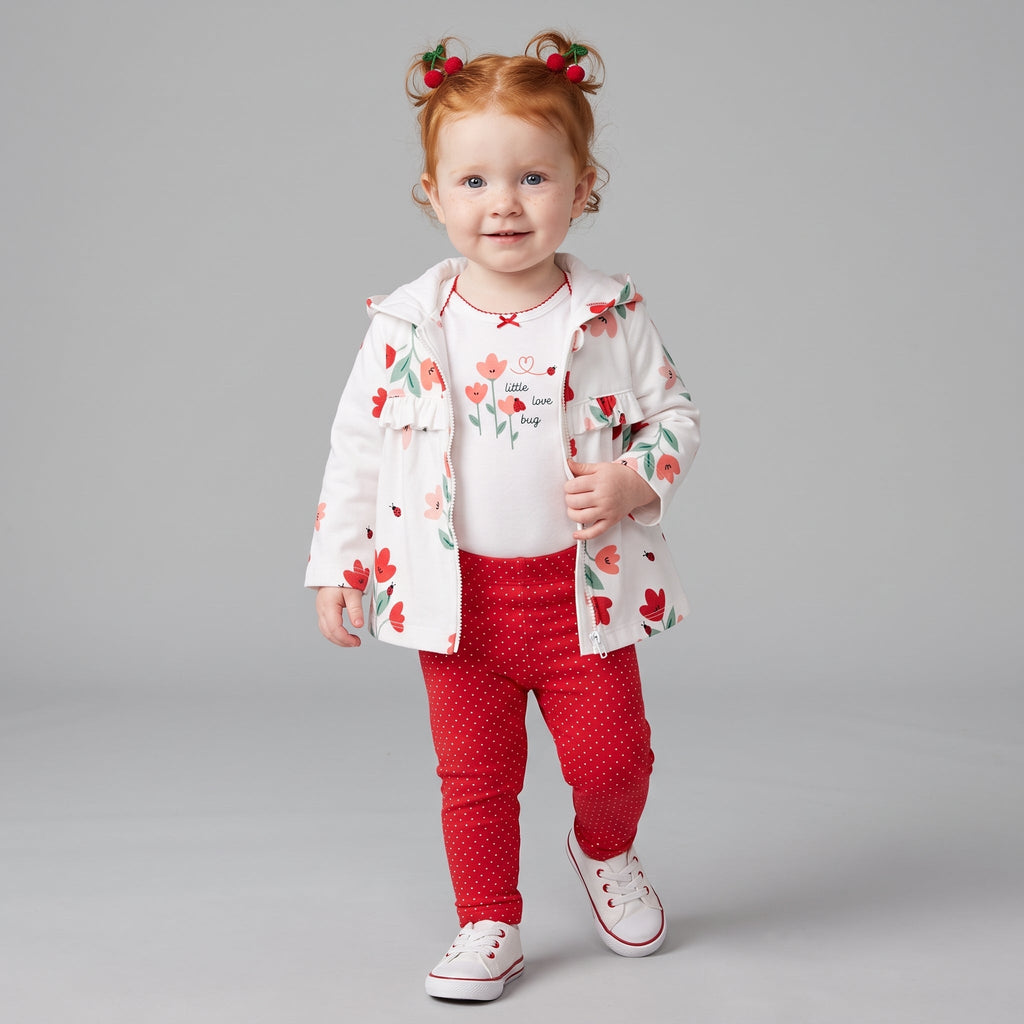 Niña pequeña vistiendo conjunto EmpiBy de tres piezas con chaqueta estampada, body blanco y leggings rojos a puntos.
