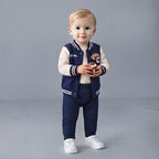 Bebé con conjunto EmpiBy de 3 piezas estilo universitario, chaqueta azul marino, body estampado y pantalón deportivo.