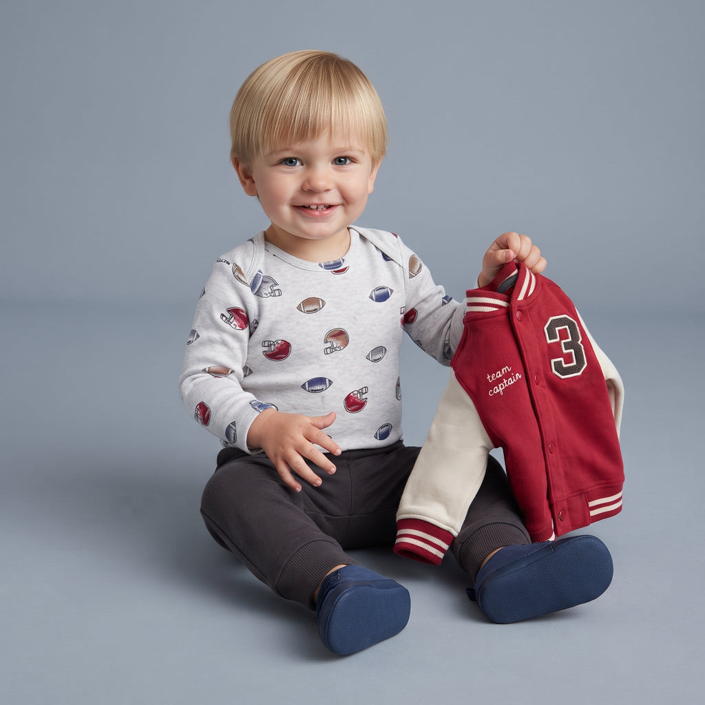 Conjunto EmpiBy de 3 piezas para bebé niño con chaqueta bomber universitaria, body estampado y pantalón gris.