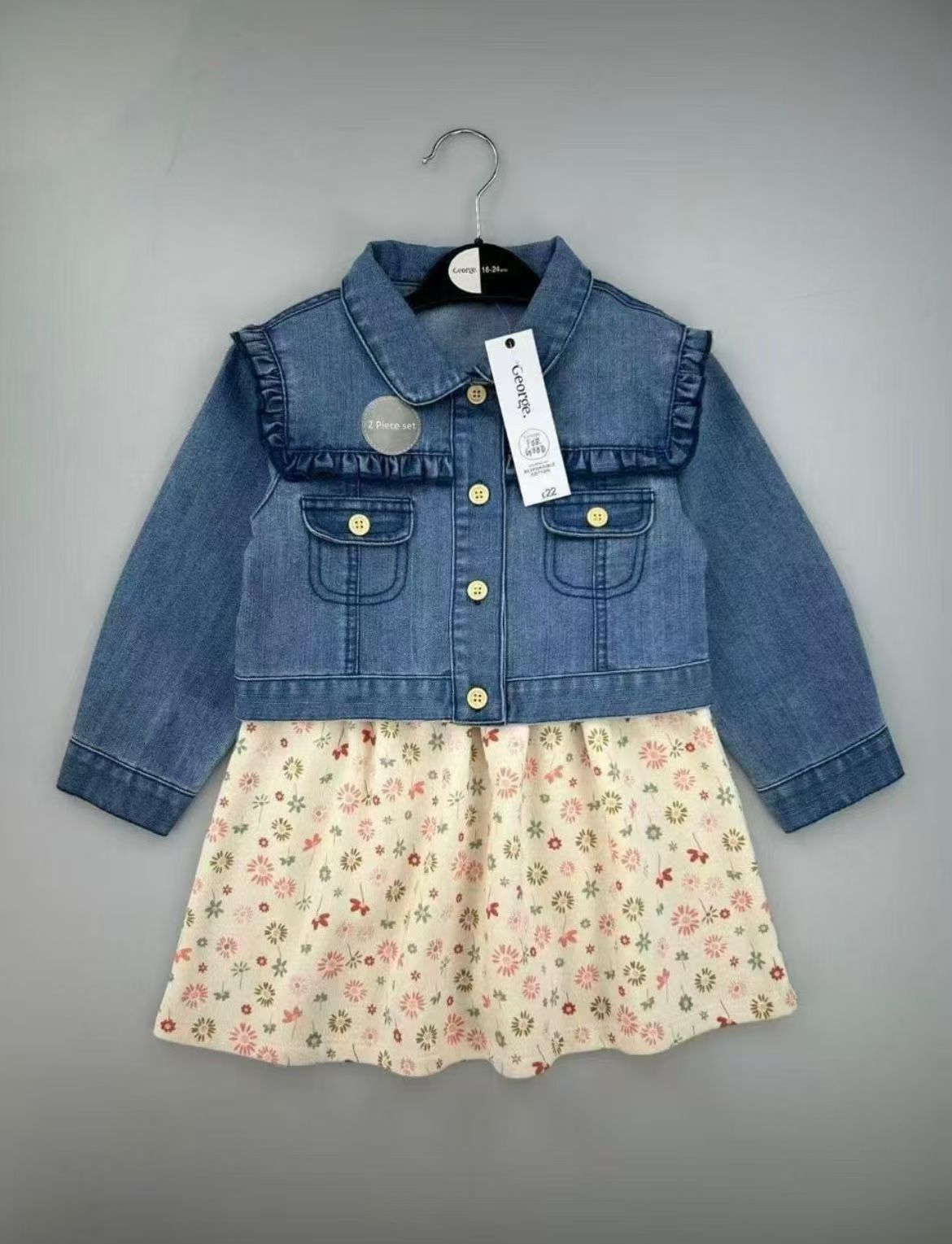 Conjunto EmpiBy para bebé niña con vestido de flores y chaqueta de mezclilla azul con volantes en los hombros.