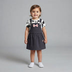 Niña pequeña vistiendo conjunto EmpiBy de vestido peto gris oscuro con lazo rosa y camiseta de Minnie Mouse