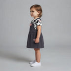 Niña pequeña vistiendo conjunto EmpiBy de vestido peto gris con lazo rosa y camiseta de Minnie Mouse