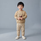 Niño vistiendo conjunto de dos piezas EmpiBy de Winnie the Pooh con sudadera beige y pantalón jogger a rayas