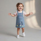 Niña feliz vistiendo conjunto EmpiBy de overall de mezclilla con bordado de Bambi y blusa rosa con estampado floral