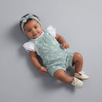 Bebé niña con conjunto EmpiBy de overol verde menta floral, camiseta blanca con volantes y diadema a juego.