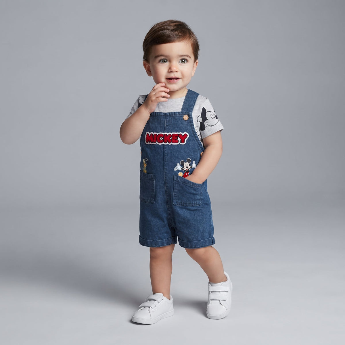 Bebé luciendo conjunto EmpiBy de 2 piezas: overol de mezclilla con bordado de Mickey y camiseta gris estampada.