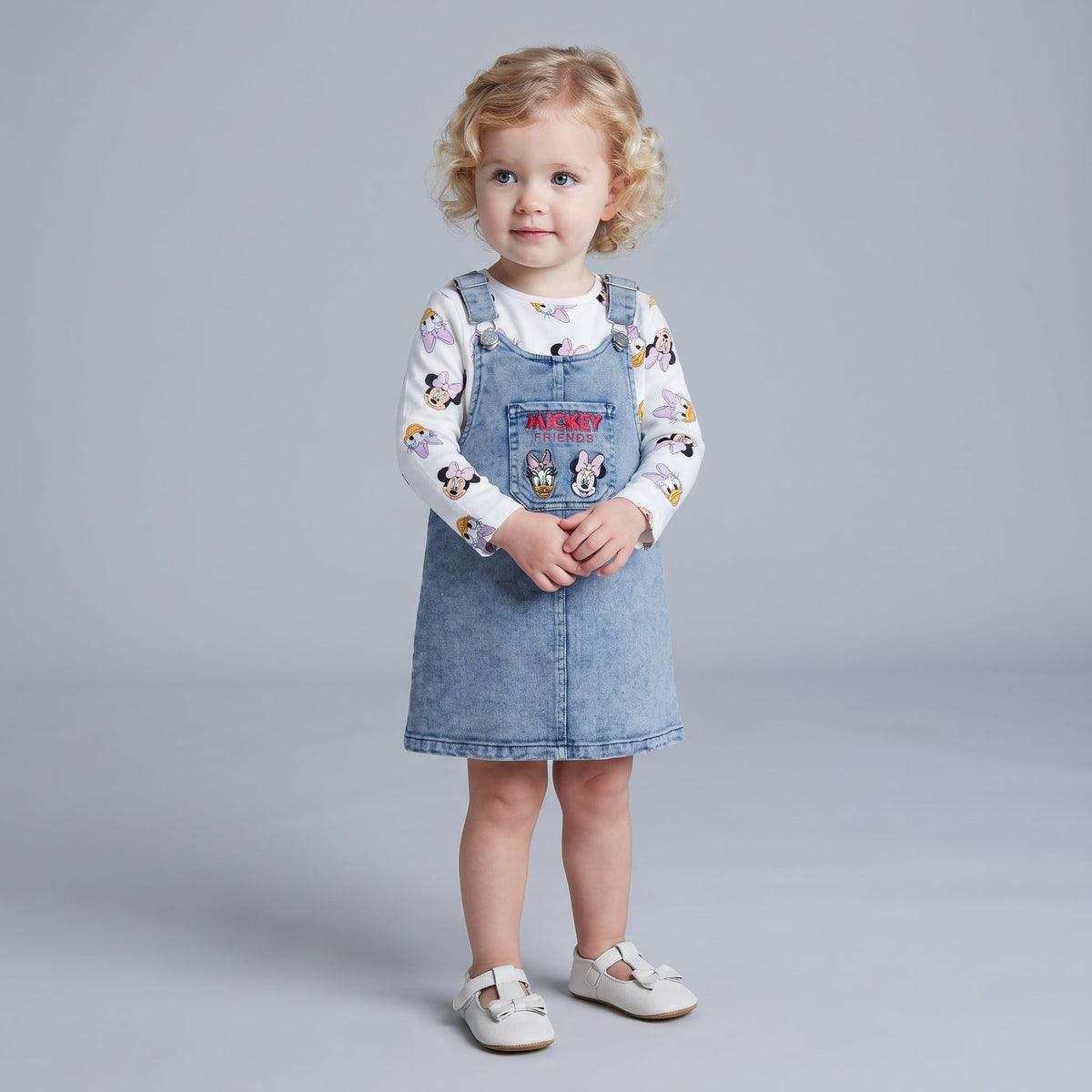 Niña pequeña vistiendo conjunto EmpiBy de overol de mezclilla con bordado de Mickey y camiseta de manga larga estampada