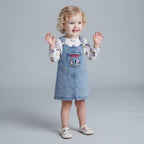 Niña pequeña con vestido overol de mezclilla EmpiBy y camiseta blanca de manga larga con estampado de Minnie Mouse