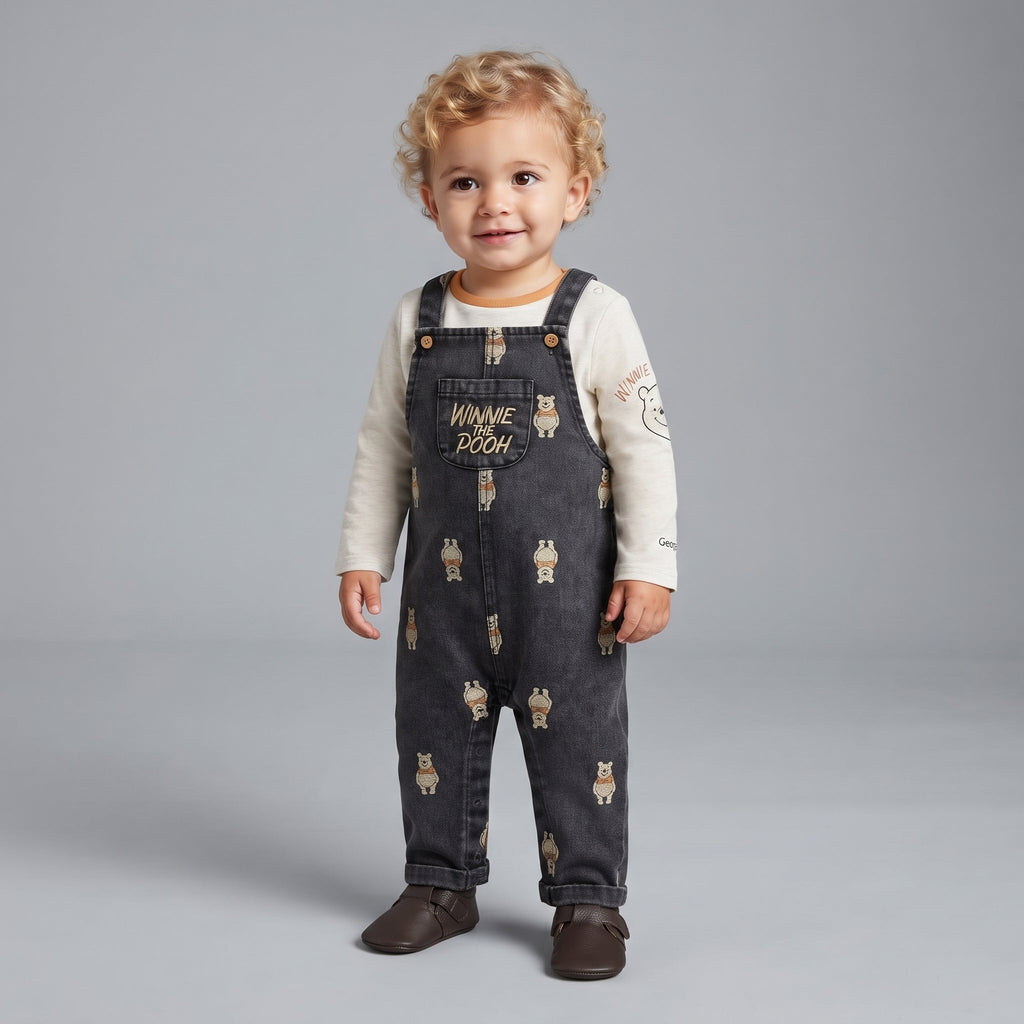 Bebé niño vistiendo overol de mezclilla oscura EmpiBy con estampado de Winnie Pooh y camiseta beige de manga larga
