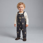 Bebé niño vistiendo overol de mezclilla oscura EmpiBy con estampado de Winnie Pooh y camiseta beige de manga larga