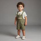 Niño pequeño vistiendo conjunto EmpiBy de overol verde oliva con estampado de Simba y camiseta blanca a rayas