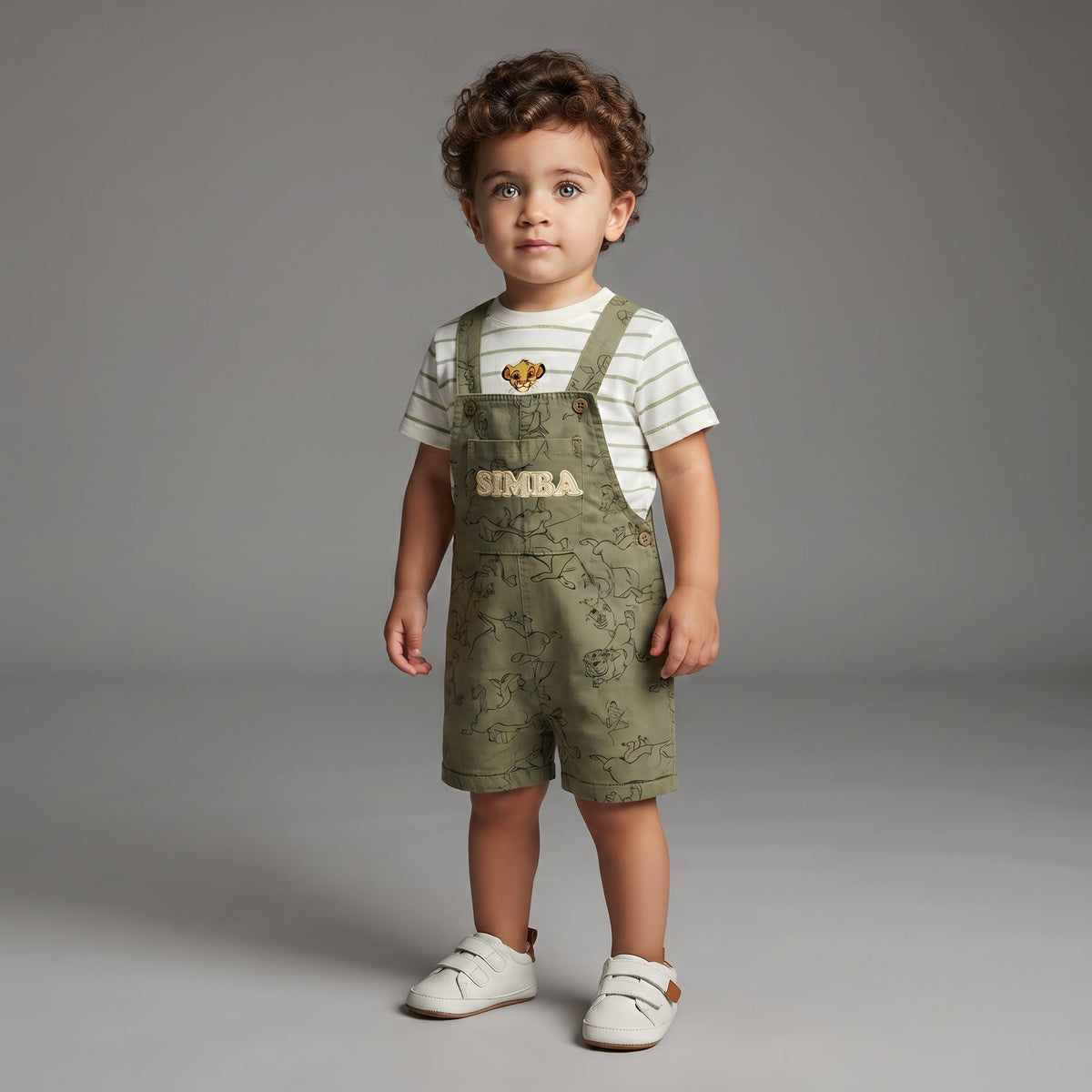 Niño pequeño vistiendo conjunto EmpiBy de overol verde oliva con estampado de Simba y camiseta blanca a rayas