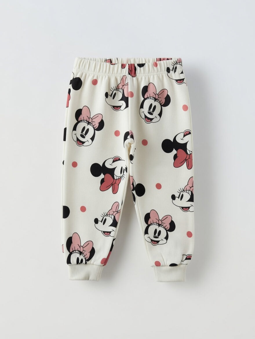 Pantalones de chándal EmpiBy para niña con estampado de Minnie Mouse, lunares y lazos sobre fondo crema suave.