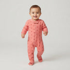 Bebé sonriente vistiendo pijama enterizo acolchado rosa con estampado de EmpiBy, tela térmica y cierre frontal