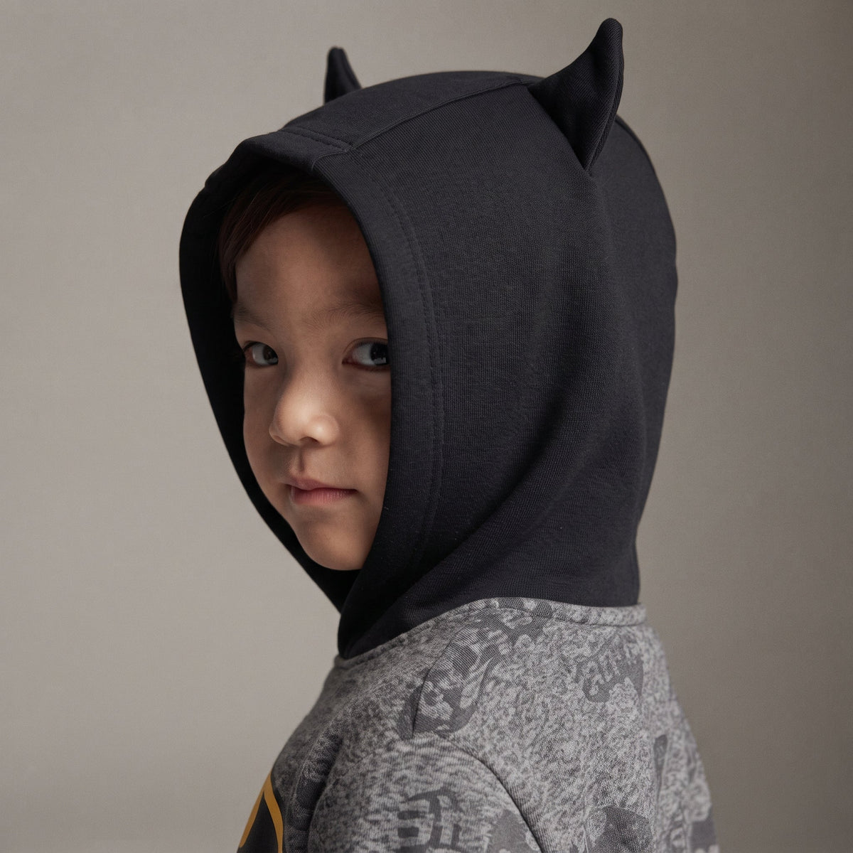 Niño vistiendo sudadera EmpiBy de Batman en gris jaspeado con capucha negra y orejas de murciélago decorativas