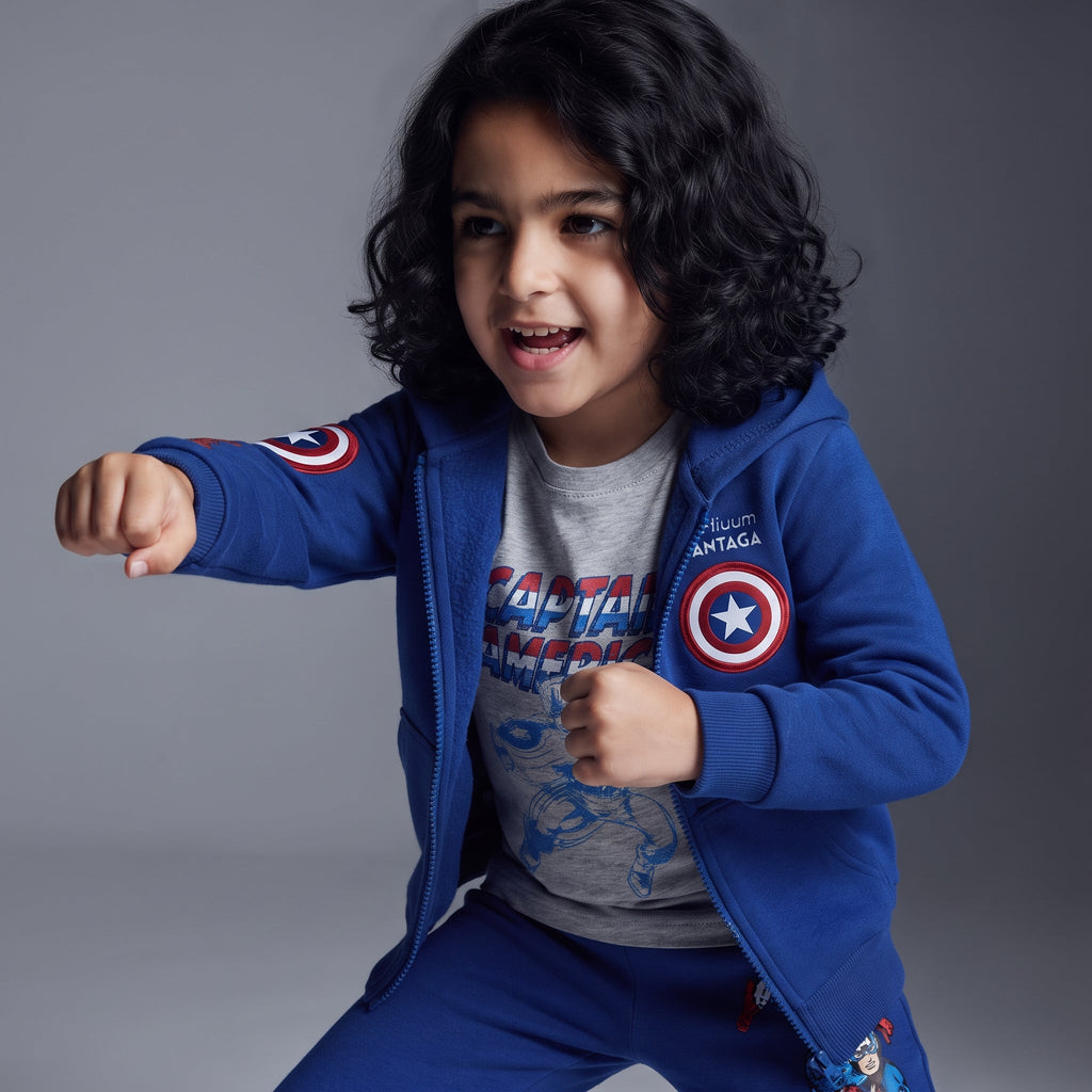 Niño posando con conjunto EmpiBy de Capitán América, sudadera azul con capucha, camiseta gris y pantalón jogger