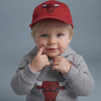 Bebé con sudadera gris EmpiBy de Chicago Bulls y gorra roja, diseño deportivo con gráfico de toro y capucha suave.