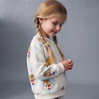 Niña con trenzas vistiendo sudadera EmpiBy de Chip y Dale con estampado de corazones celestes sobre fondo claro