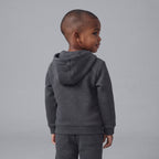 Niño de espaldas vistiendo sudadera con capucha y pantalón jogger gris oscuro de EmpiBy con temática de Disney