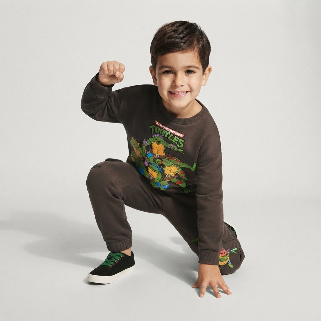 Niño sonriente vistiendo sudadera y pantalón de invierno EmpiBy con estampado de las Tortugas Ninja en color marrón