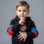 Niño vistiendo sudadera negra con capucha EmpiBy de Mario Bros con detalles en rojo y azul sobre fondo gris