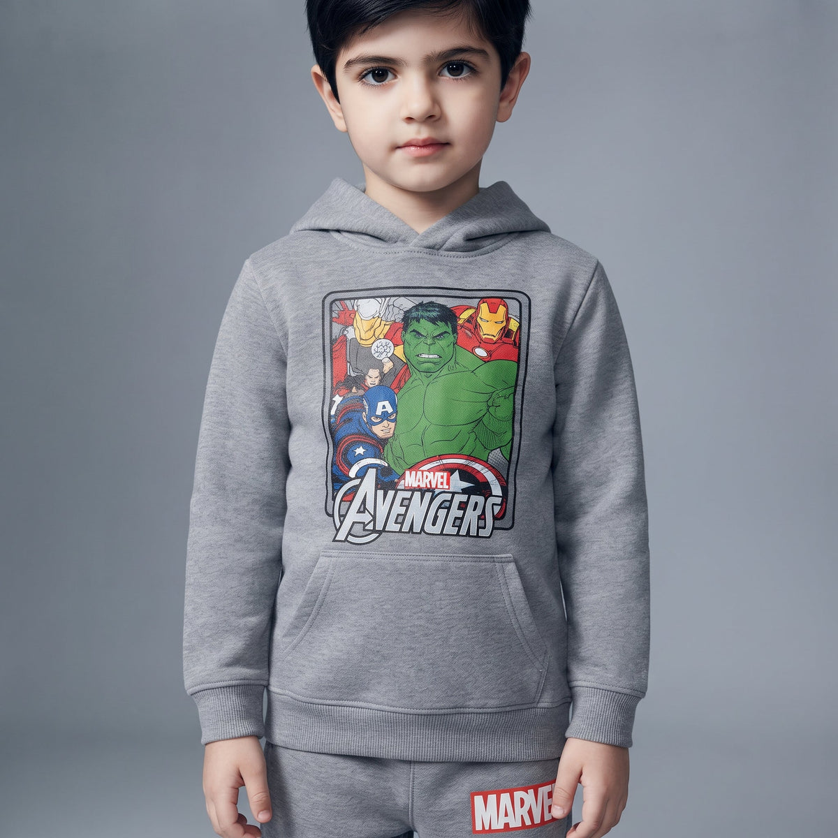 Niño vistiendo conjunto EmpiBy de sudadera gris con capucha y estampado de Avengers y pantalón jogger a juego.