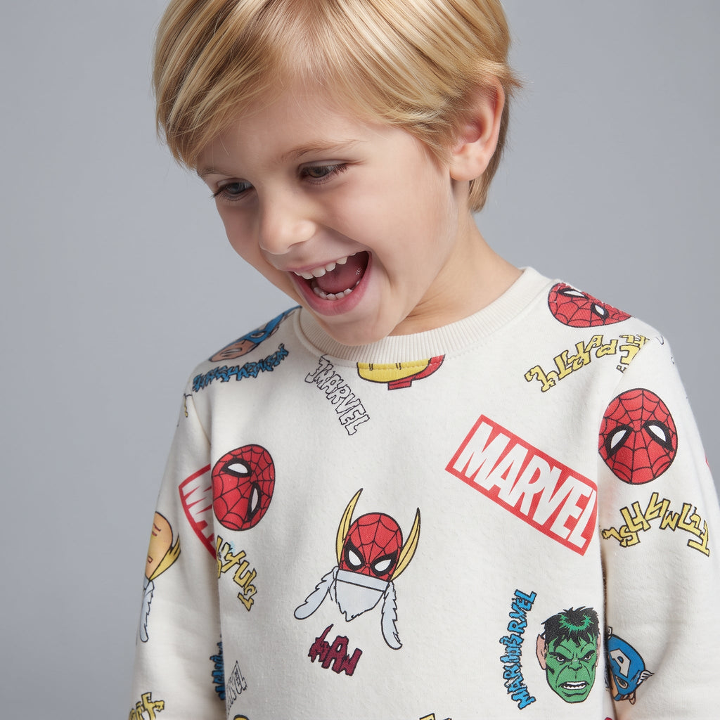Niño sonriente vistiendo sudadera EmpiBy de color marfil con estampado colorido de superhéroes de Marvel