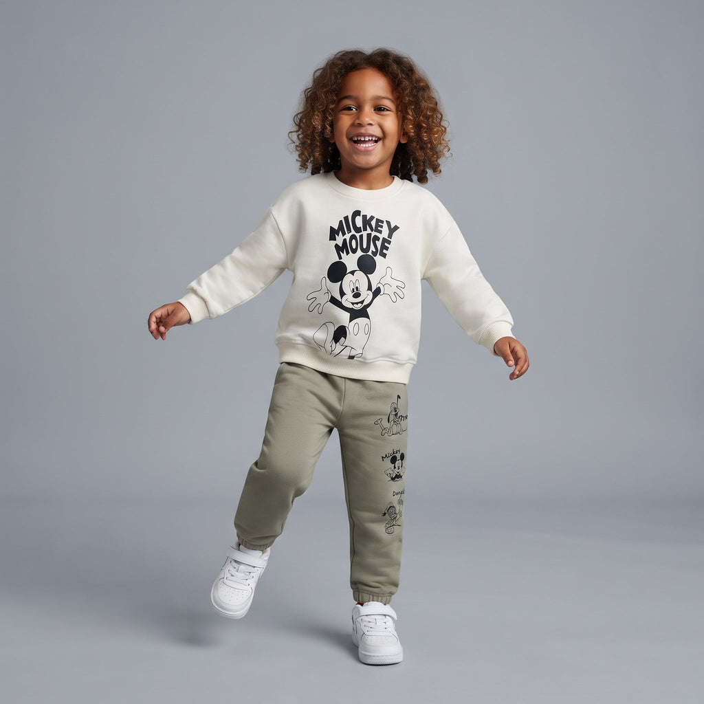 Niño sonriente con sudadera EmpiBy marfil de Mickey Mouse y pantalón jogger verde oliva con estampado de personajes