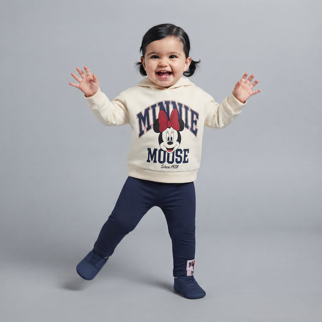 Bebé feliz vistiendo conjunto EmpiBy de dos piezas con sudadera crema de Minnie Mouse y pantalón jogger azul marino
