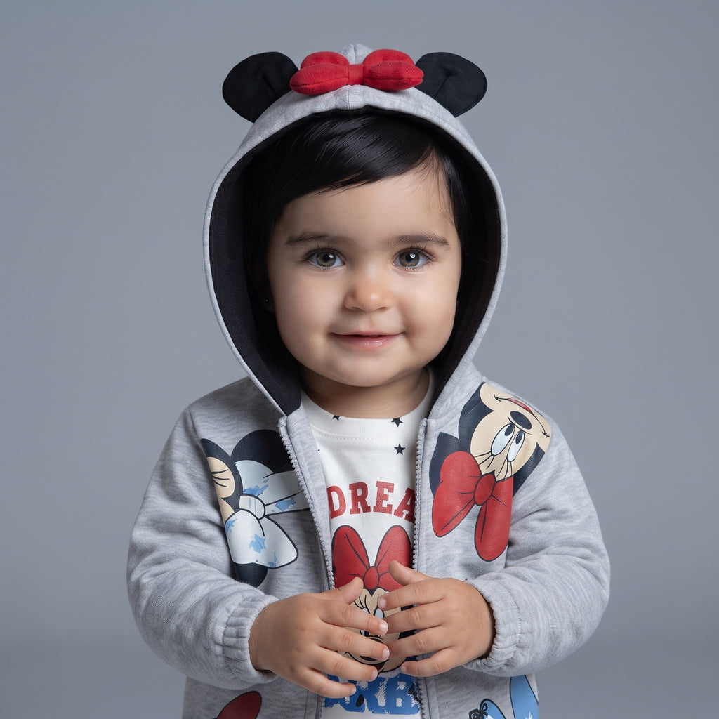 Bebé sonriente con sudadera gris EmpiBy de Minnie Mouse con capucha, orejas y lazo rojo sobre camiseta estampada