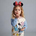 Niña con sudadera EmpiBy de Minnie Mouse y Daisy, con capucha rosa y estampado colorido, estilo casual y cómodo.