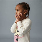Niña con sudadera EmpiBy color marfil de Minnie Mouse con gráfico frontal y cuello redondo en estudio