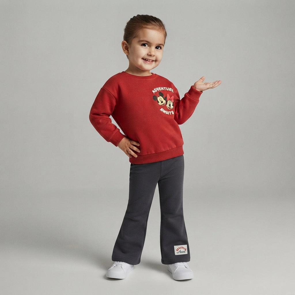 Niña sonriente vistiendo sudadera roja EmpiBy de Minnie Mouse con estampado urbano y pantalones grises