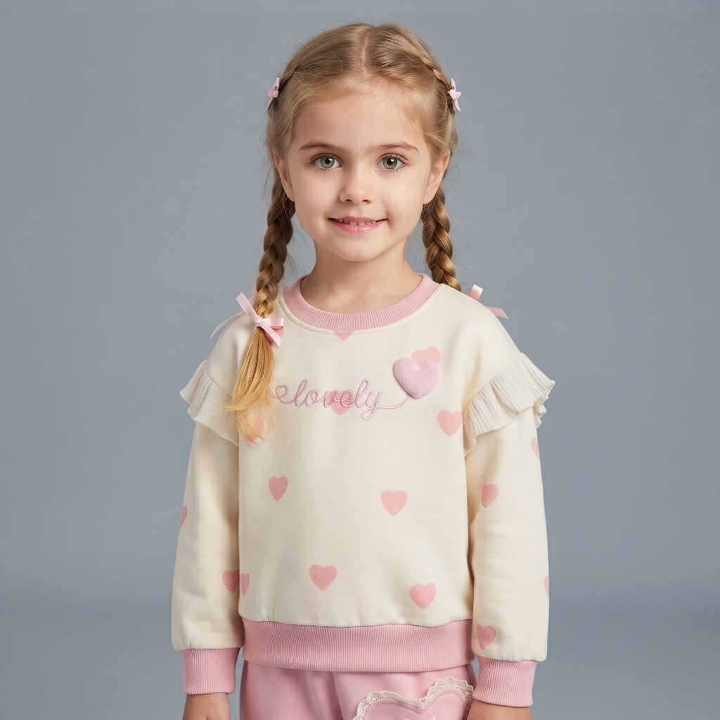 Niña con conjunto EmpiBy de sudadera crema con corazones rosas, volantes de encaje y lazos, estilo tierno y cómodo.