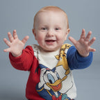 Bebé feliz vistiendo sudadera EmpiBy de Pato Donald con mangas rojas y azules, estilo cómodo y divertido.