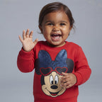 Niña pequeña sonriente vistiendo sudadera roja EmpiBy con estampado de Minnie Mouse y lazo azul brillante