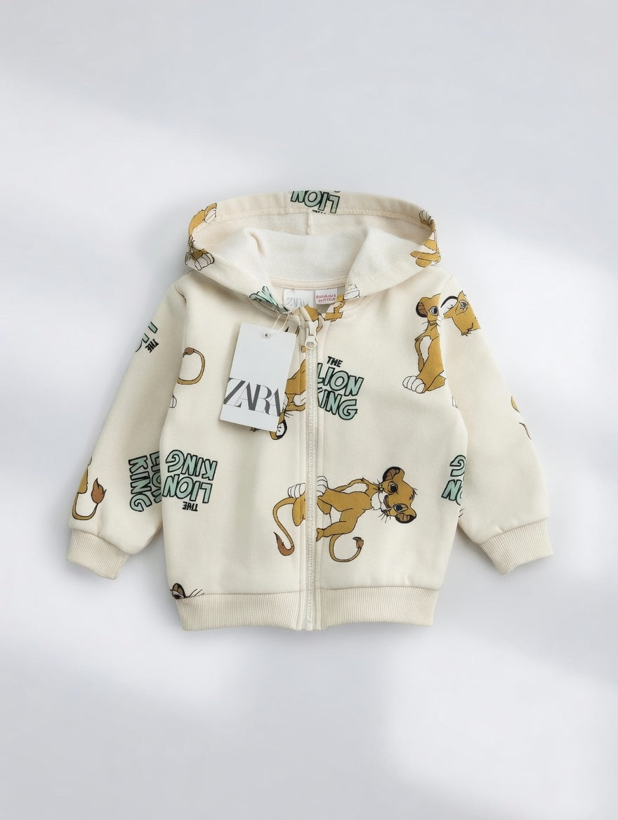 Sudadera EmpiBy con capucha y cremallera, color crema con estampado de Simba de El Rey León para niños.